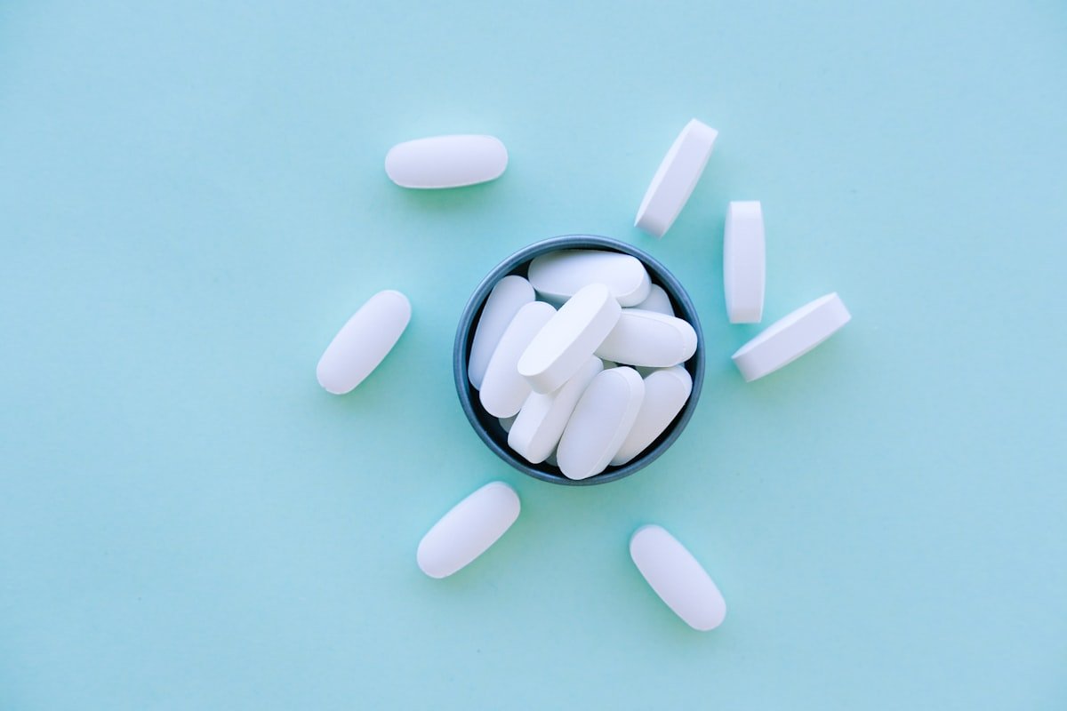 Capsules and supplements arranged in a bowl on a dark blue surface