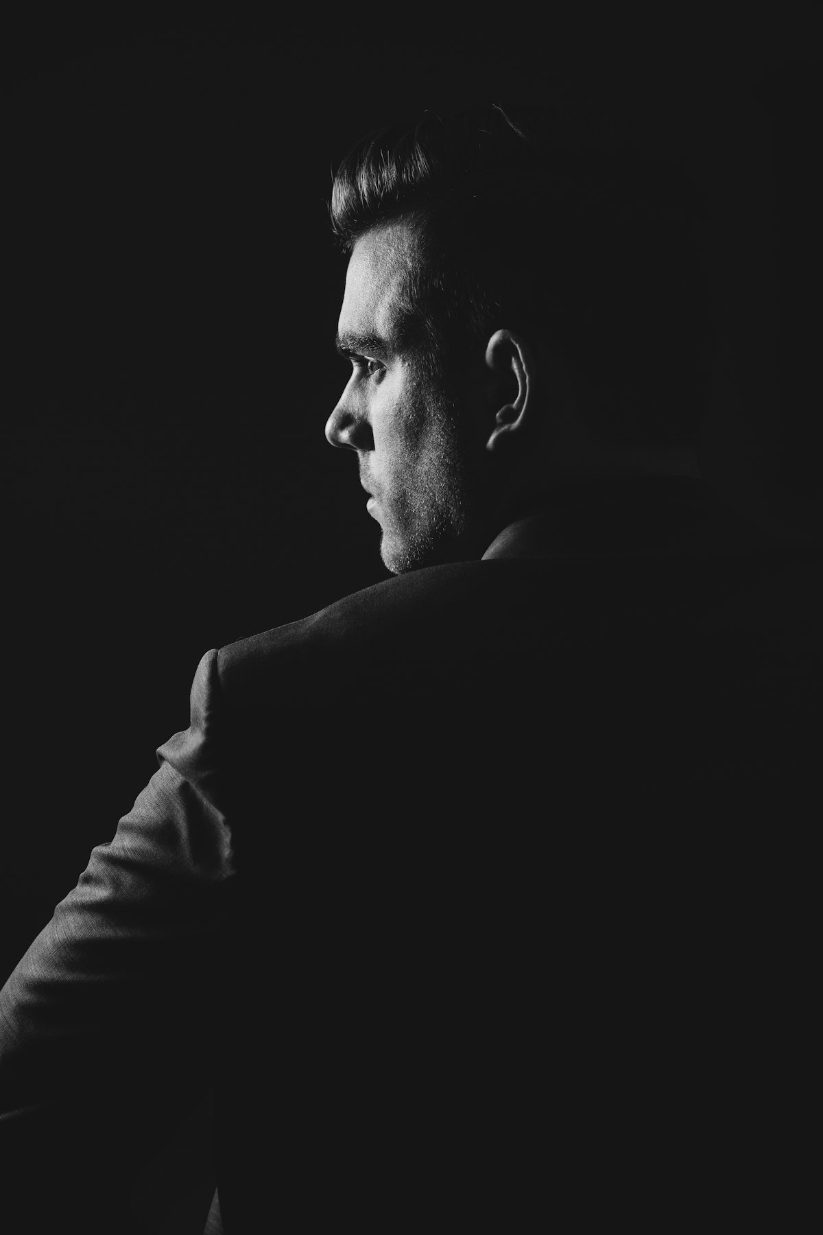 Editorial portrait of a confident man in blazer against a dark background
